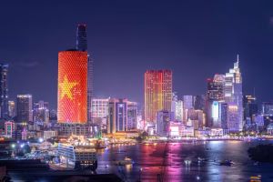 Ho Chi Min skyline at night with a Vietnamese flag emblem lighting up the side of one skyscraper
